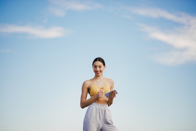 Linda chica con entrenamiento telefónico en cielo azul