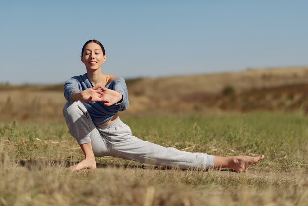 Linda chica entrenando en el cielo azul en un campo