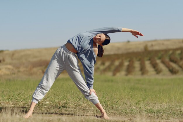 Linda chica entrenando en el cielo azul en un campo