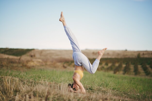 Linda chica entrenando en el cielo azul en un campo