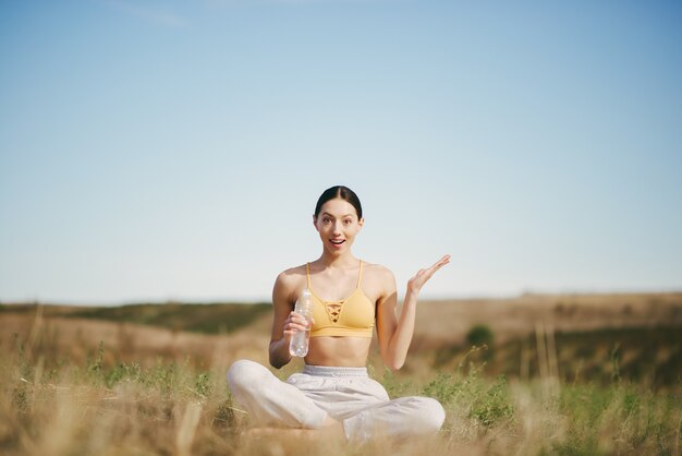 Linda chica entrenando en el cielo azul en un campo