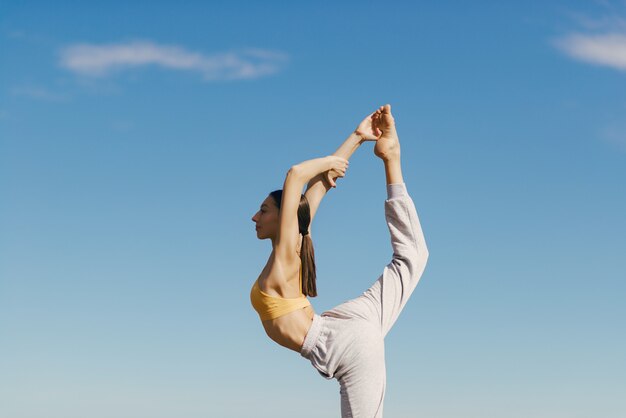 Linda chica entrenando en cielo azul