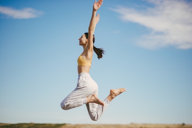 Foto gratuita linda chica entrenando en cielo azul