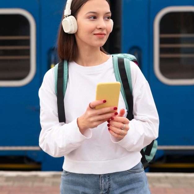 Linda chica en la estación de tren escuchando música