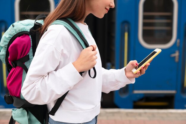 Linda chica en la estación de tren con su teléfono inteligente