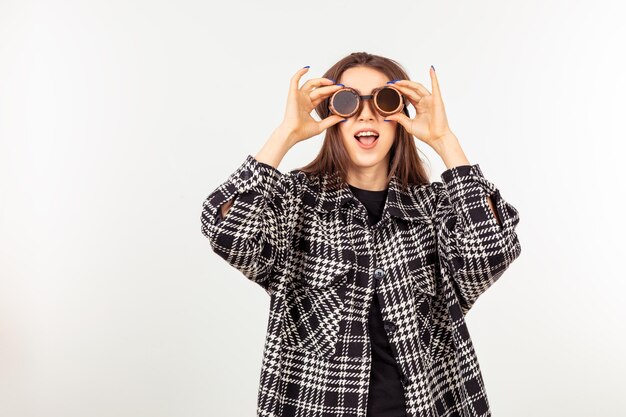 Una linda chica con gafas de piloto viejas y parada en un fondo blanco