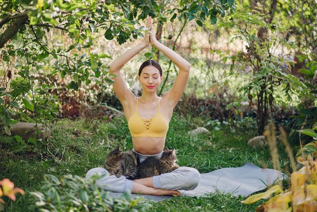 Linda chica con un gato entrenando en un patio de verano