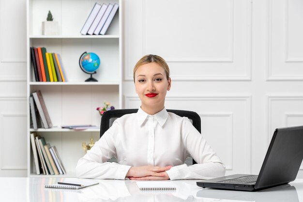 Linda chica guapa de servicio al cliente en camisa blanca con lápiz labial rojo y portátil sonriendo