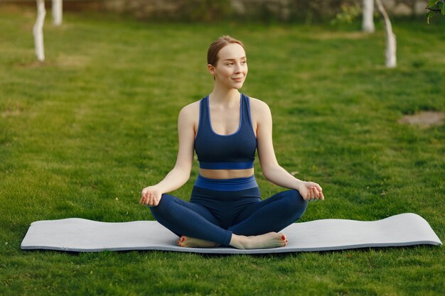 Linda chica haciendo yoga en un parque de verano