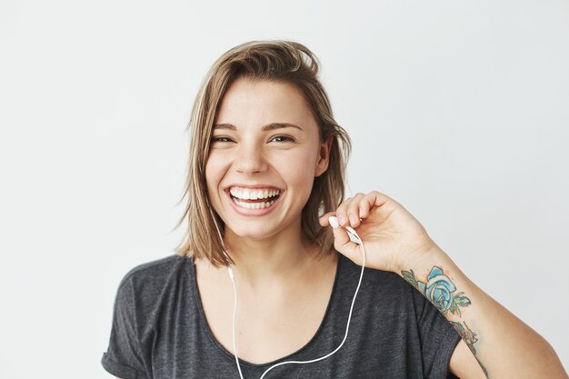 Linda chica joven en auriculares riendo.