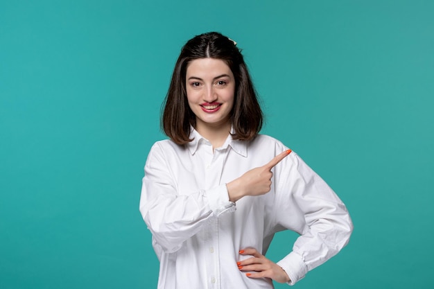 Linda chica joven bastante adorable chica morena en camisa blanca apuntando a la derecha y sonriendo