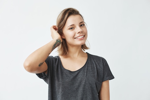 Linda chica joven y bella sonrisa corrigiendo el cabello.