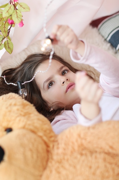 Linda chica jugando con bombillas de luz de la cama