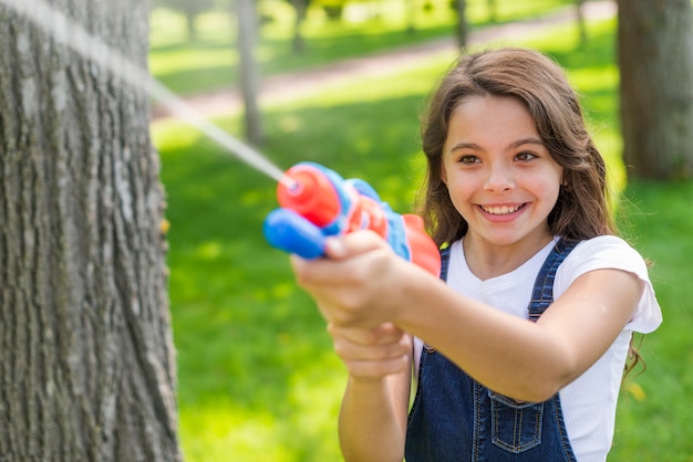 Linda chica jugando con una pistola de agua