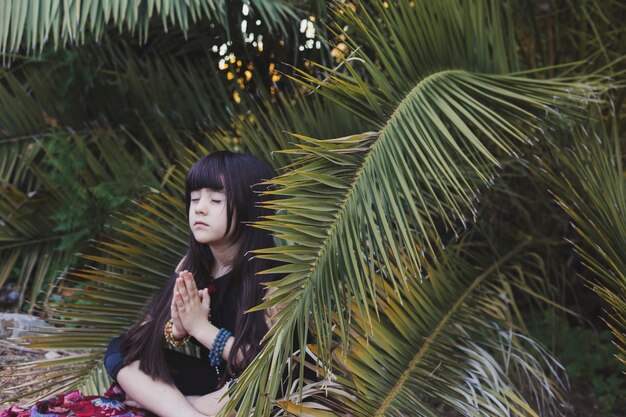 Linda chica meditando cerca de la palma