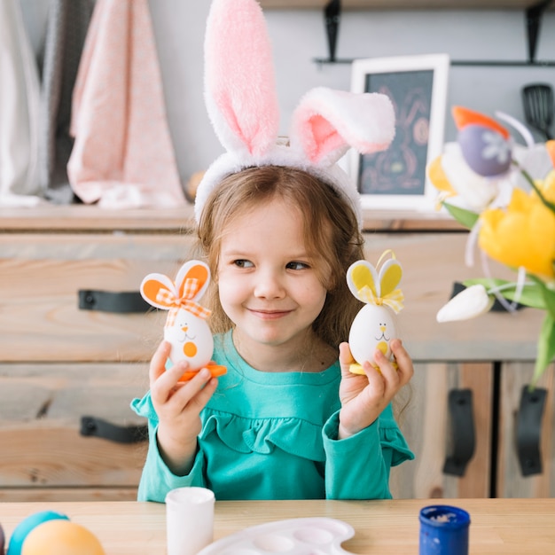 Linda chica en orejas de conejo con huevos de Pascua