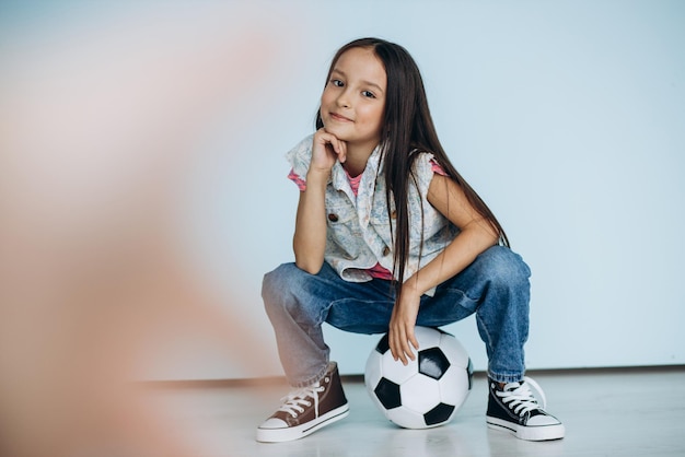 Linda chica con pelota de fútbol en el estudio