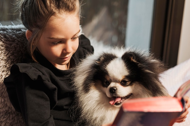 Foto gratuita linda chica y perro leyendo