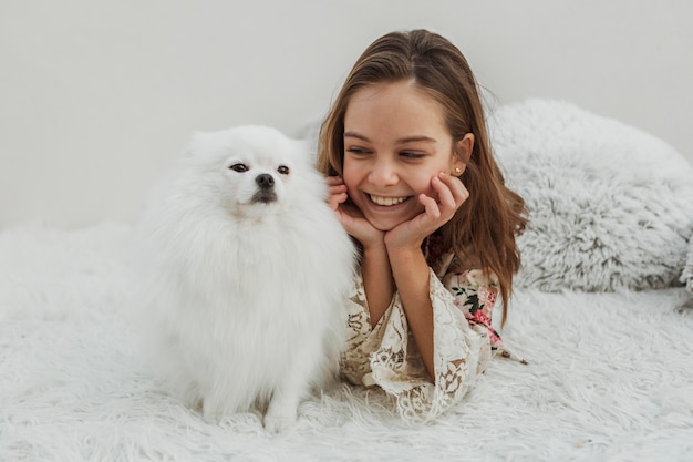 Linda chica y perro sentado en la cama