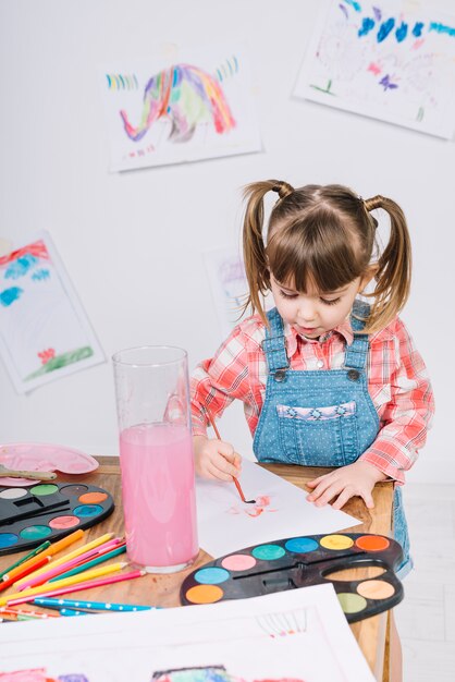 Linda chica pintando con acuarela sobre papel