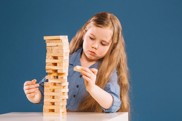 Linda chica quitando bloques de la torre jenga