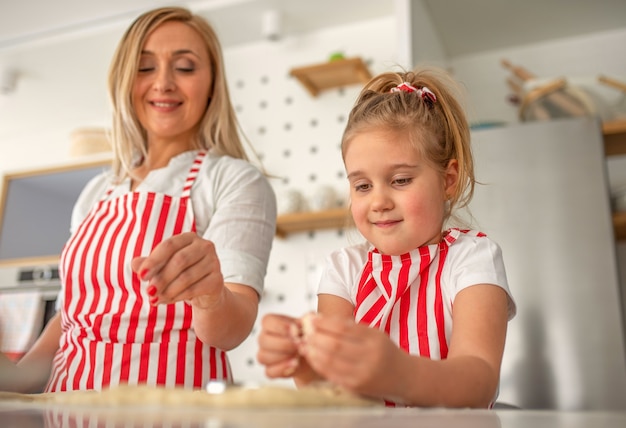 Linda chica rubia cocinando felizmente con su madre