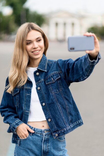 Linda chica rubia tomando una foto del uno mismo al aire libre