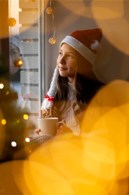 Foto gratuita linda chica sintiéndose acogedora con su taza en navidad