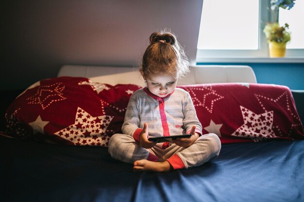 Linda chica con smartphone en la cama