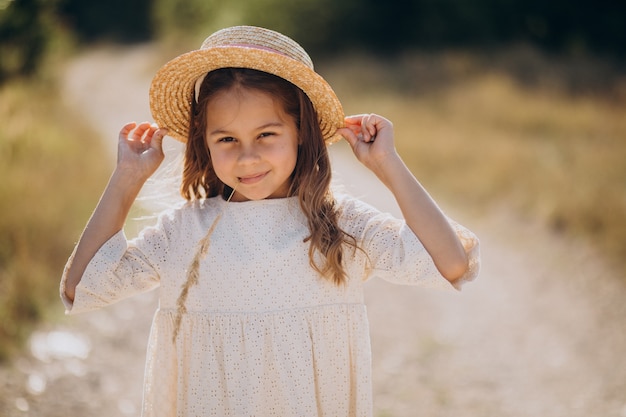 Linda chica con sombrero caminando en la pradera
