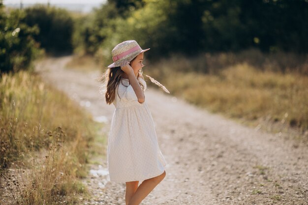 Linda chica con sombrero caminando en la pradera