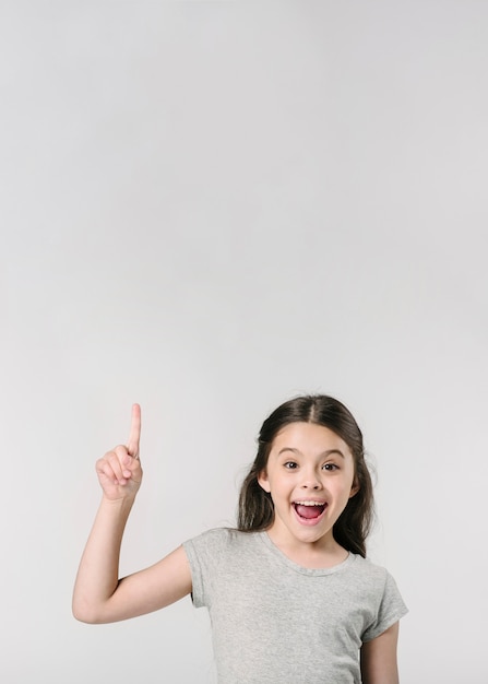 Linda chica sonriendo con el dedo en el estudio