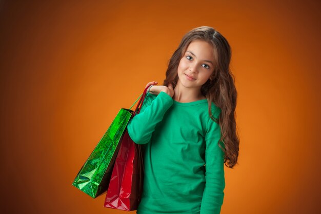 Linda chica con suéter verde con bolsas de compras