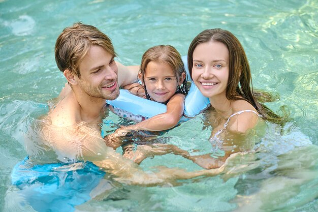 Linda chica y sus padres pasan tiempo en la piscina