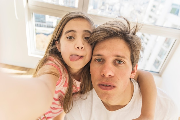 Linda chica tomando selfie divertido con su padre