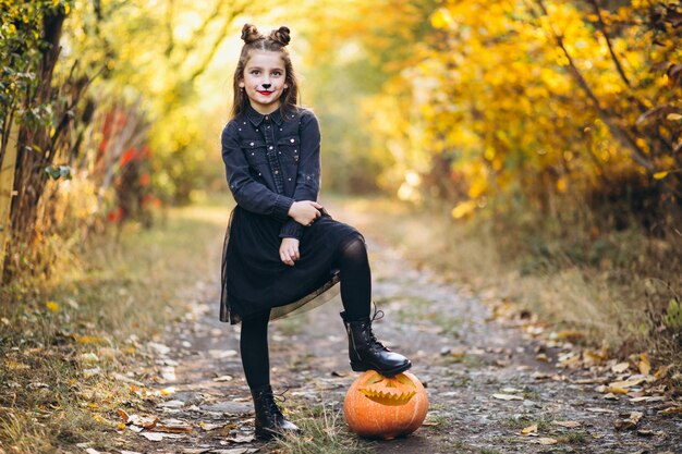 Linda chica vestida con disfraz de halloween al aire libre con calabazas