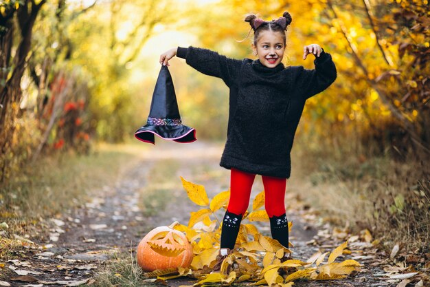 Linda chica vestida con disfraz de halloween al aire libre con calabazas