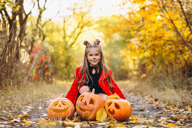 Linda chica vestida con disfraz de halloween al aire libre con calabazas