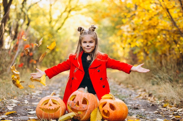 Linda chica vestida con disfraz de halloween al aire libre con calabazas