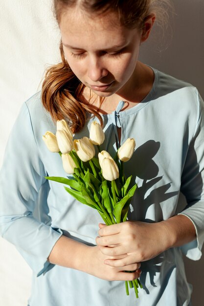 Linda dama sosteniendo tulipanes de cerca