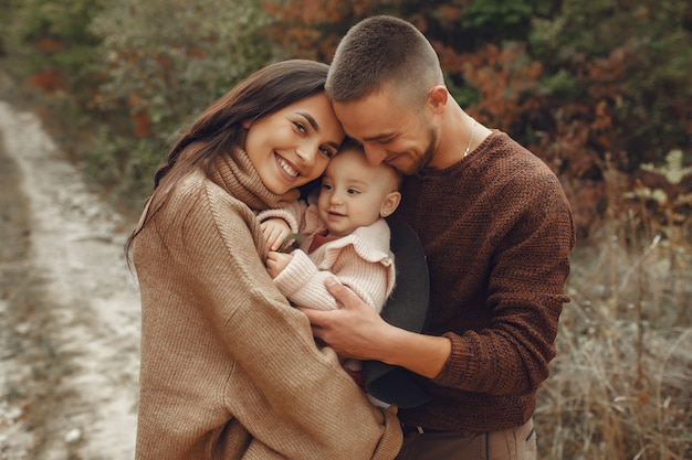 Linda y elegante familia jugando en un campo de otoño