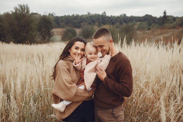 Linda y elegante familia jugando en un campo de otoño