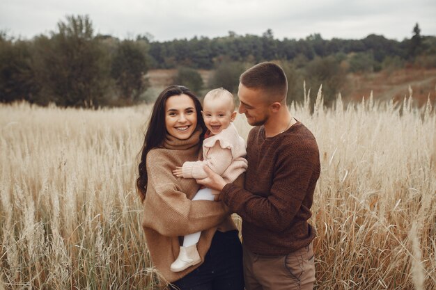 Linda y elegante familia jugando en un campo de otoño