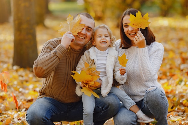 Linda y elegante familia jugando en un campo de otoño