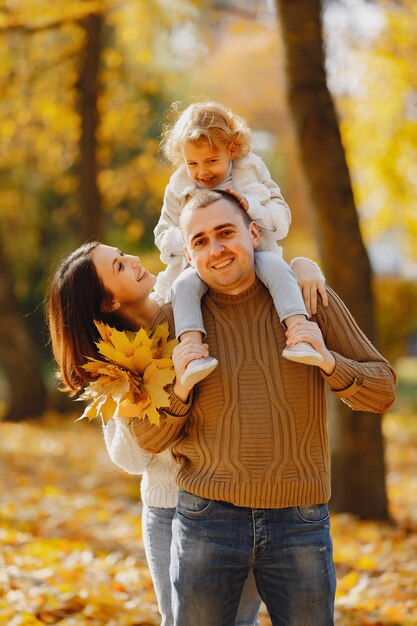 Linda y elegante familia jugando en un campo de otoño