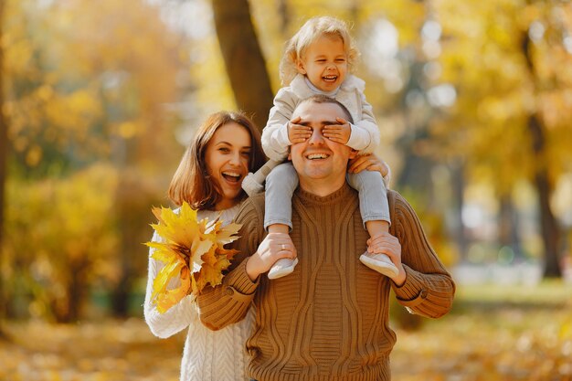 Linda y elegante familia jugando en un campo de otoño