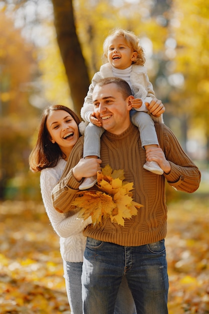 Linda y elegante familia jugando en un campo de otoño