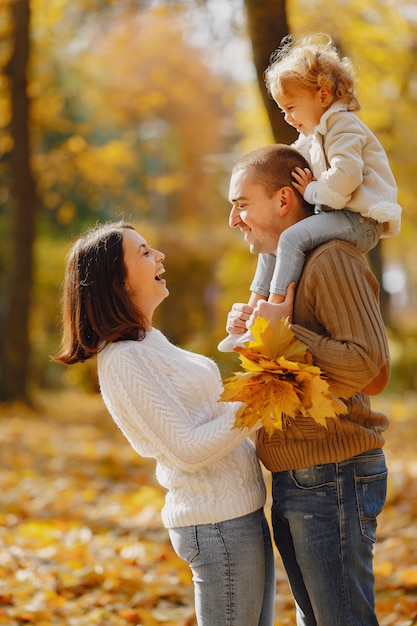 Linda y elegante familia jugando en un campo de otoño