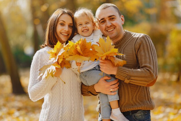 Linda y elegante familia jugando en un campo de otoño