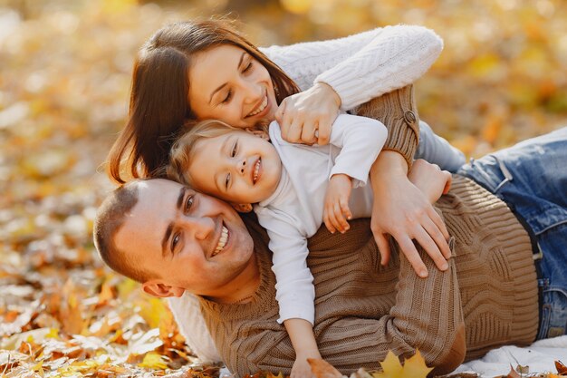 Linda y elegante familia jugando en un campo de otoño